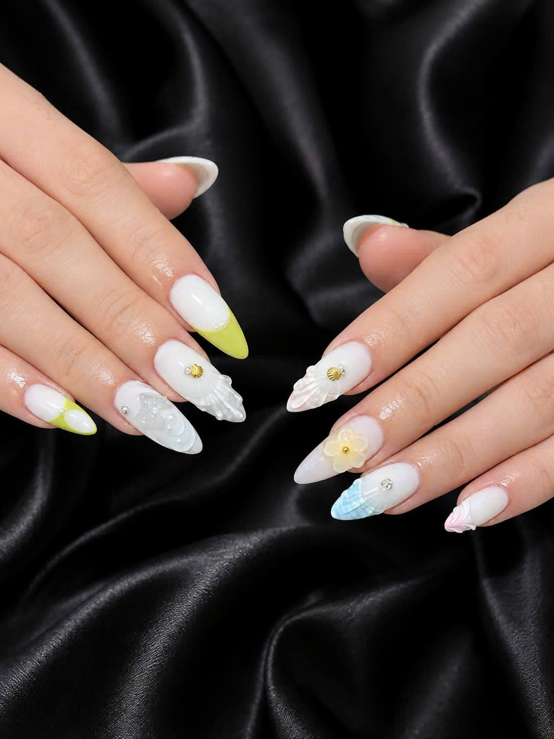 White nail art with pastel tips, shell textures, pearls, and a floral accent