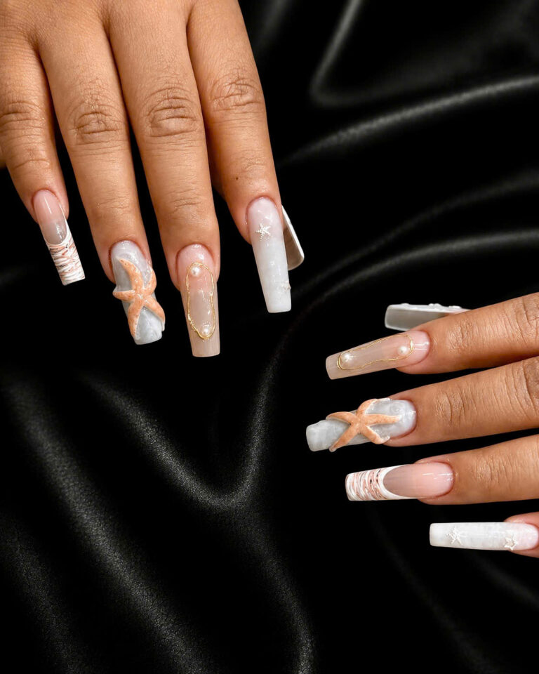 Long nude and white square nails with pearl, ribbon and floral details on black silk