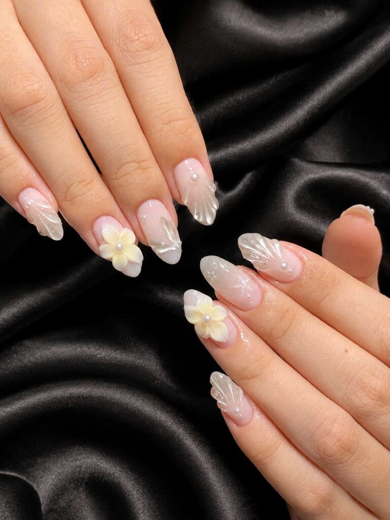 Soft pink nails with white floral and shell accents on black silk