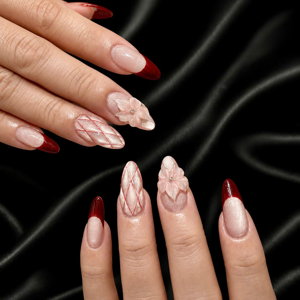 Burgundy and blush almond nails with sculpted floral details on black silk