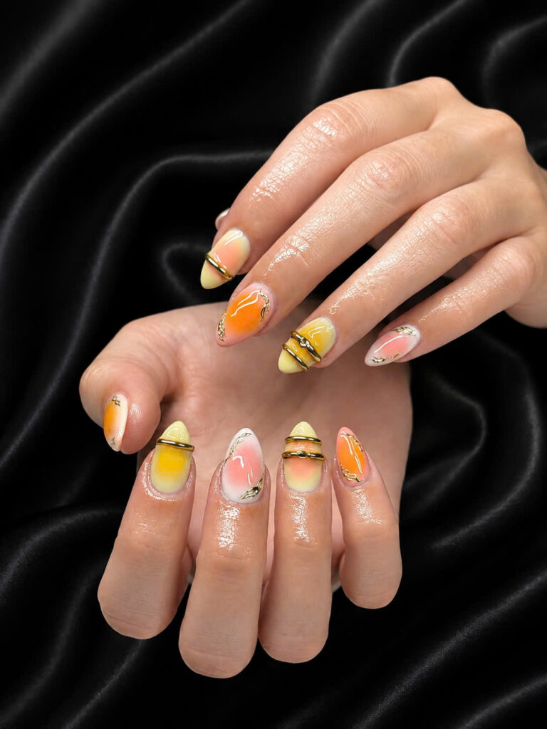 Orange, yellow and pink nail art with gold accents on black silk